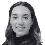 Smiling woman in a black turtleneck, with shoulder-length wavy hair. The black-and-white photo conveys a professional and friendly tone.